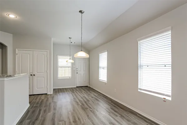 a view of an empty room with window and wooden floor