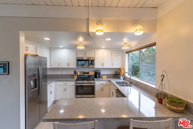 a kitchen with stainless steel appliances granite countertop a sink a stove and a refrigerator