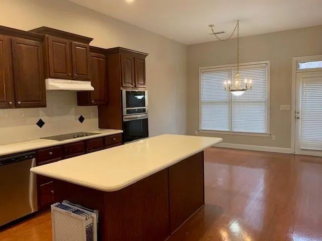 a kitchen with stainless steel appliances a kitchen island a stove a refrigerator and cabinets