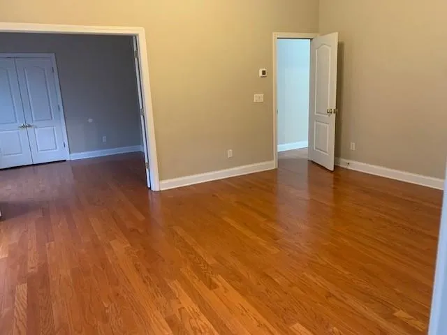 a view of an empty room with wooden floor and closet