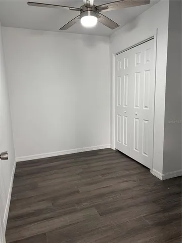 a view of empty room with wooden floor and fan