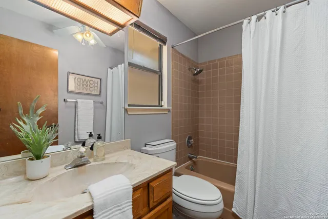 a bathroom with a granite countertop sink a toilet and shower