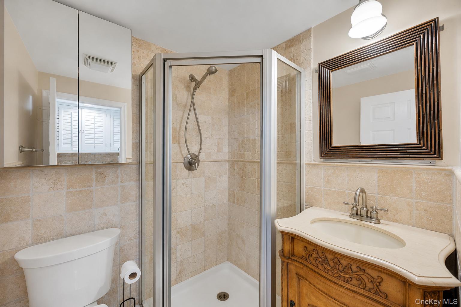 19 Joan Road Bay Shore, NY 11706 - Photo 37 of 50 Bathroom featuring a corner shower with a glass enclosure, a vanity with an ornate wood-finish base and light-colored countertop, and a decorative framed mirror
