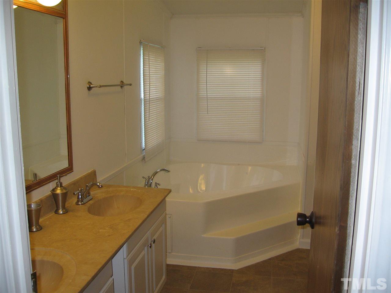 155 Charlie Fields Road Pittsboro, NC 27312 - Photo 14 of 25 Master bath has totally new garden tub & newdouble sinks with new cabinets. Separate shower with elegant showerhead is to the right of tub. Toilet is separated from the rest. Has entry to bedroom & to utility room.
