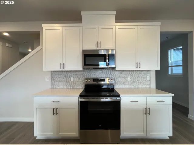 a kitchen with white cabinets and black appliances