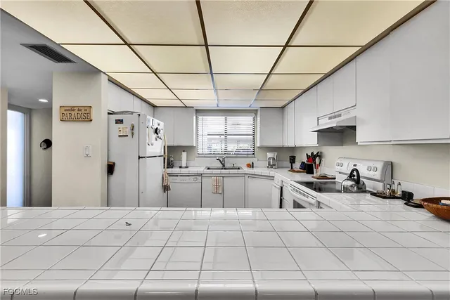 a kitchen with stainless steel appliances granite countertop a sink a stove a refrigerator cabinets and a window