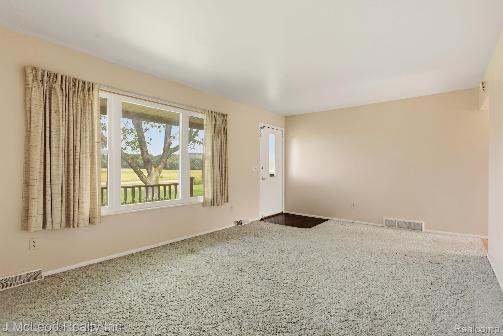 9481 Swaffer Road Vassar, MI 48768 - Photo 8 of 39 Carpeted living space featuring a large picture window, an entry door with a vertical glass insert, and neutral wall tones