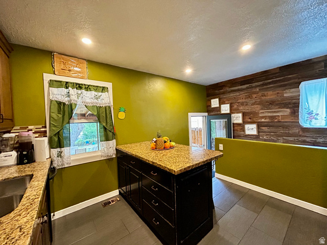 1931 Harrison Boulevard Ogden, UT 84401 - Photo 5 of 21 Kitchen featuring recessed lighting, a central island with a granite-style countertop, dark wood-finish cabinetry, and a wood plank accent wall