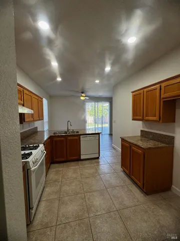 a large kitchen with stainless steel appliances a large counter top a stove top oven a sink dishwasher and granite counter top