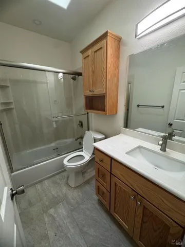 a bathroom with a granite countertop sink a toilet a mirror and shower