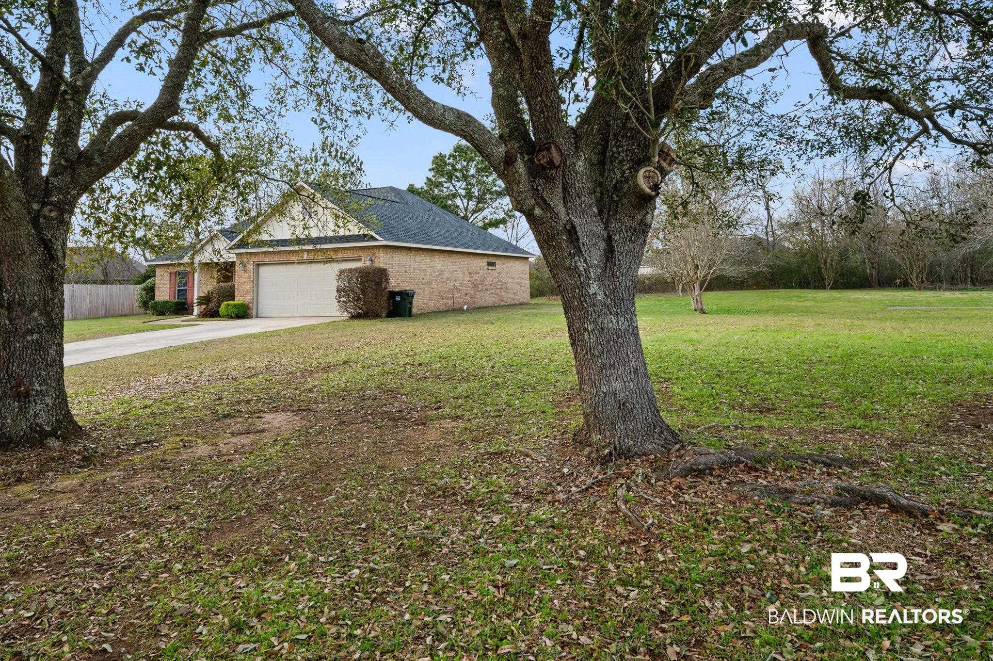 9381 Sable Court Daphne, AL 36526 - Photo 35 of 42 View of side of property with a yard, concrete driveway, an attached garage, and brick siding