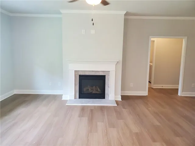 a view of an empty room with wooden floor a fireplace and a window