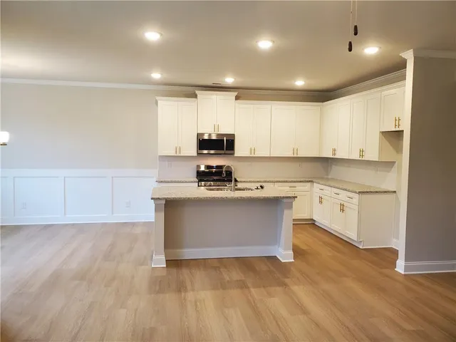 a view of kitchen with granite countertop stainless steel appliances sink and cabinets