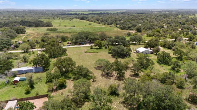 an aerial view of residential houses with outdoor space and trees