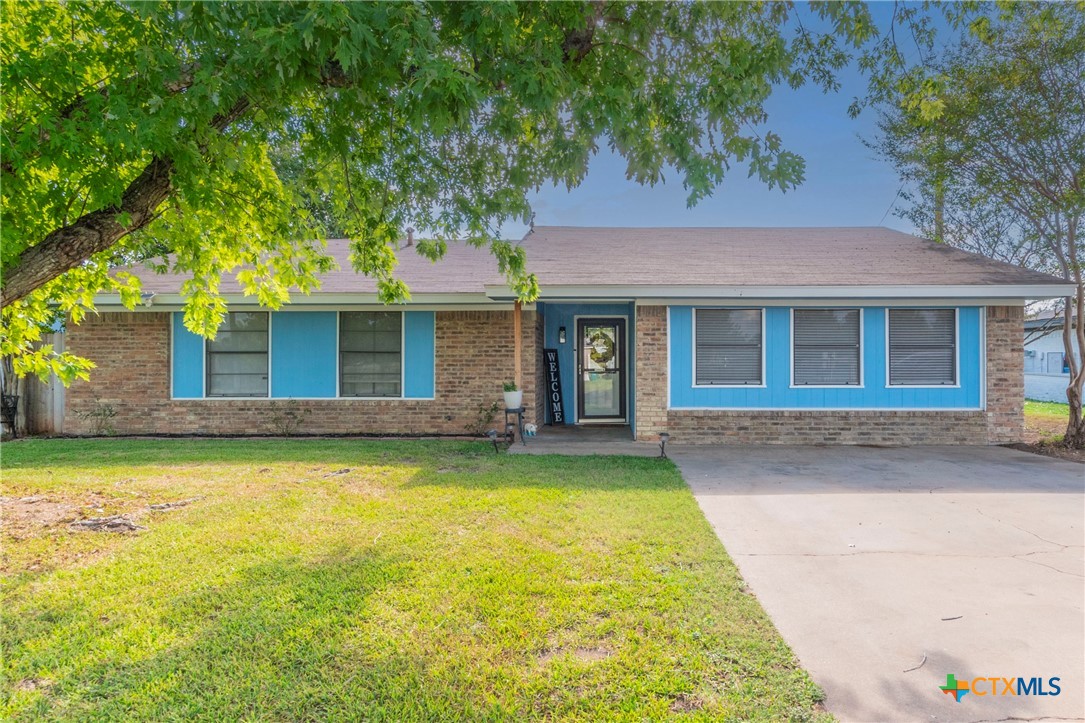 Front exterior of single-story home with mature trees and front lawn
