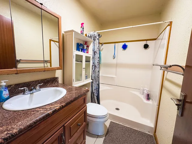 a bathroom with a granite countertop sink toilet and shower