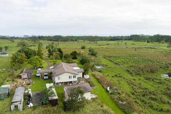an aerial view of a house with green landscape and water view