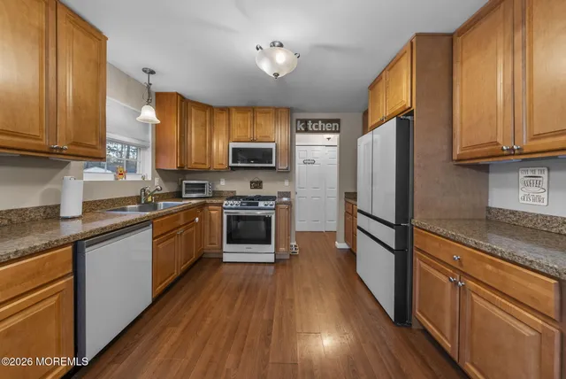 a kitchen with granite countertop wooden floors stainless steel appliances a sink and a window