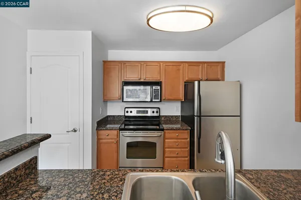 a kitchen with granite countertop a sink stove and cabinets