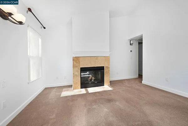 a view of empty room with floor to ceiling window and fireplace