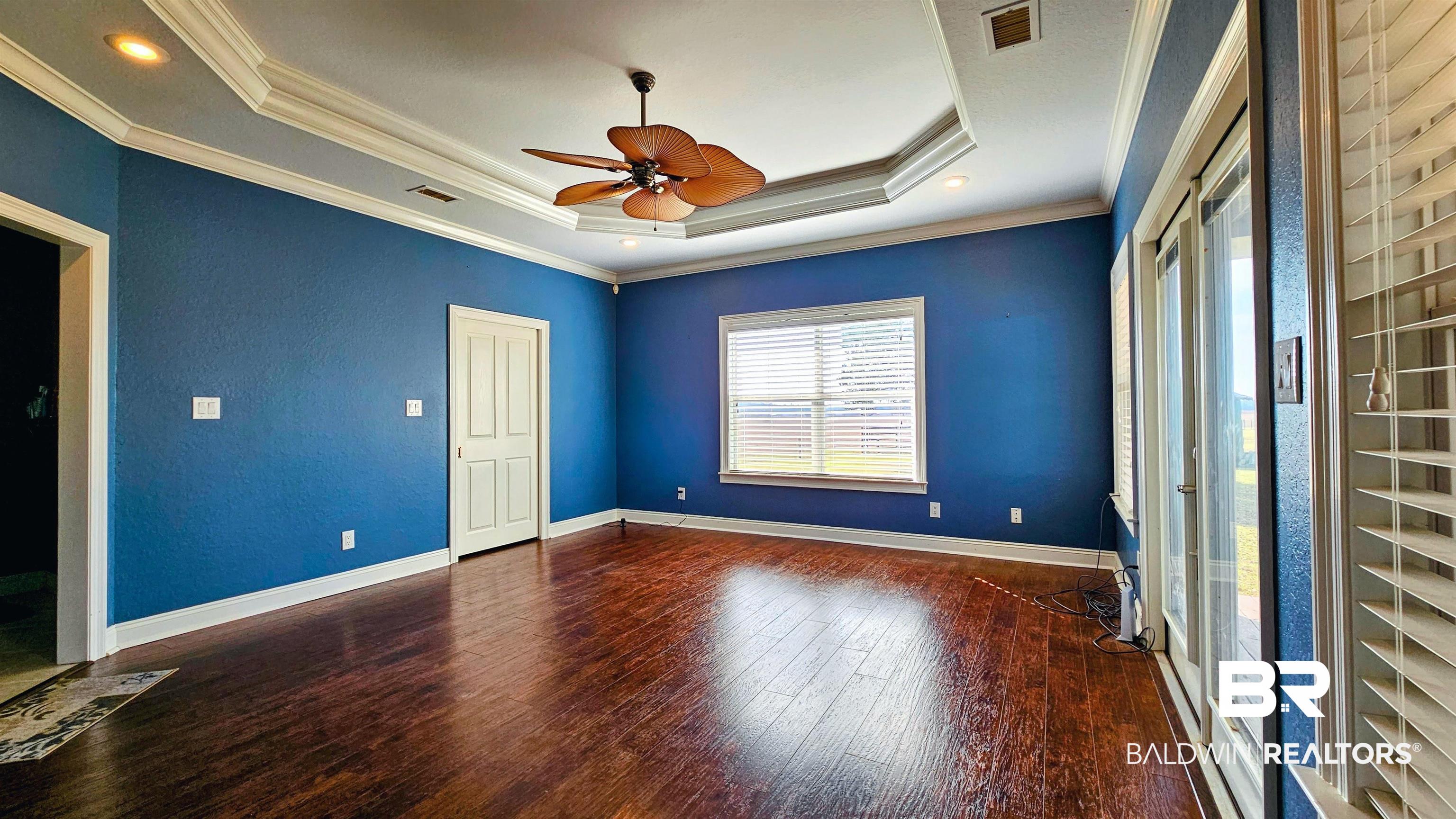 9275 Crawford Road Elberta, AL 36530 - Photo 11 of 28 Unfurnished bedroom featuring dark wood-style flooring, a tray ceiling, ornamental molding, and a ceiling fan