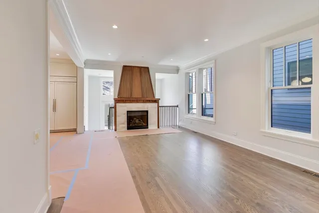 an empty room with wooden floor fireplace and windows