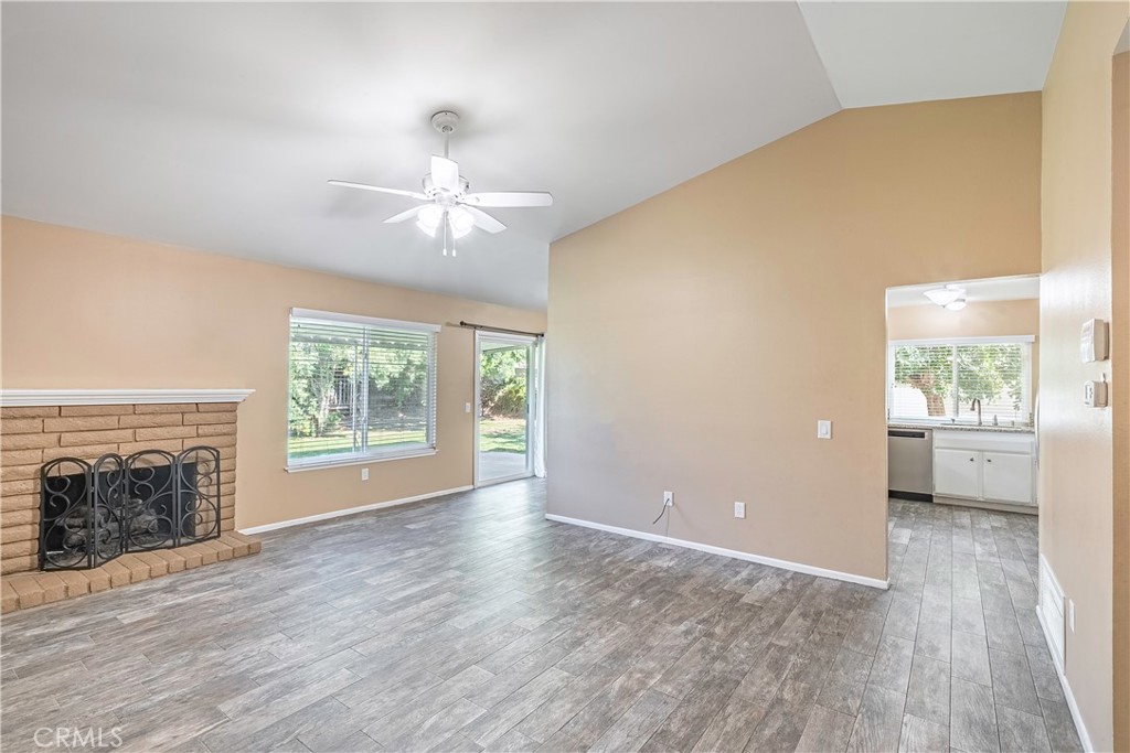 2415 Peppertree Lane Riverside, CA 92506 - Photo 4 of 39 an empty room with windows a fireplace and a chandelier fan
