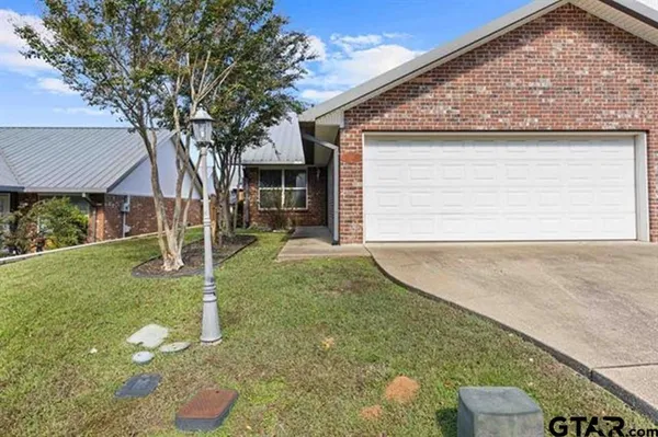 a backyard of a house with plants and large tree