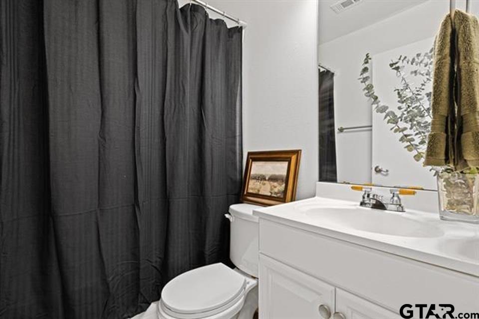 1807 Paverstone Lane Longview, TX 75605 - Photo 14 of 37 a bathroom with a sink a toilet and shower curtain