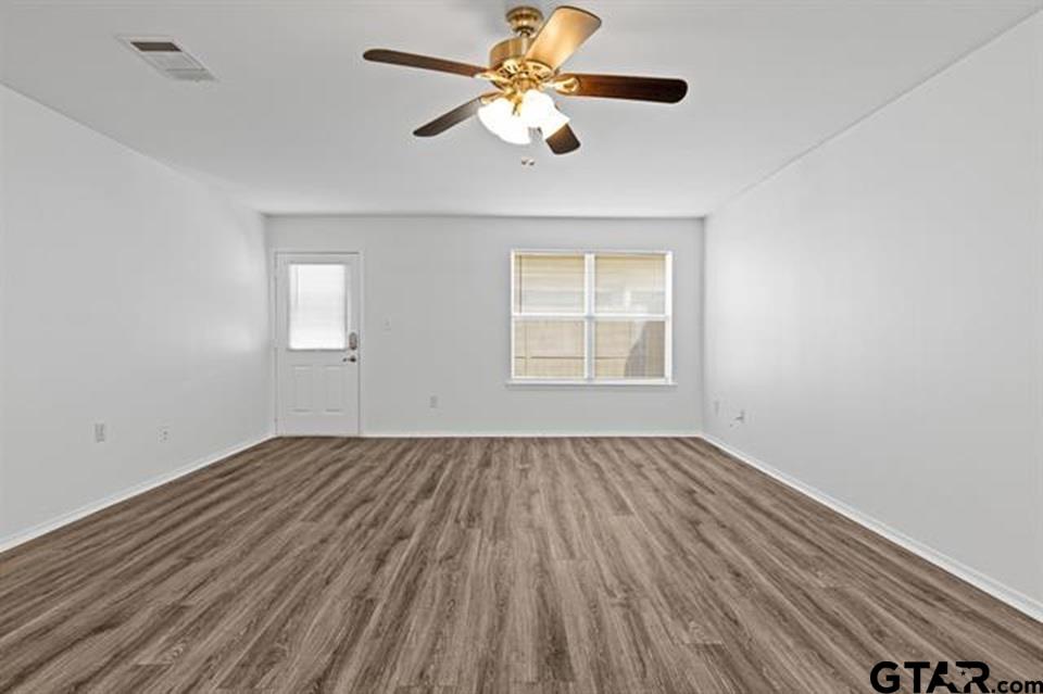 1807 Paverstone Lane Longview, TX 75605 - Photo 18 of 37 an empty room with wooden floor chandelier fan and windows