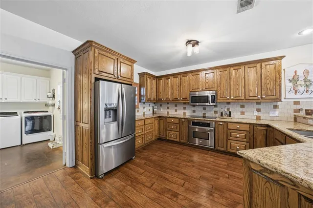 a kitchen with granite countertop wooden floors stainless steel appliances and window