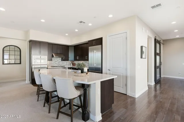 a living room with furniture kitchen view and a chandelier