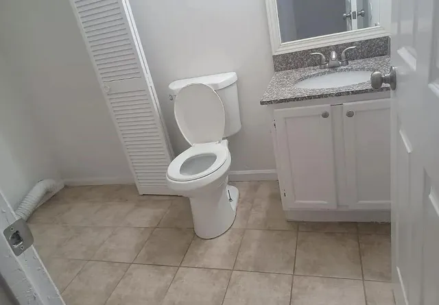 a bathroom with a granite countertop sink and a toilet