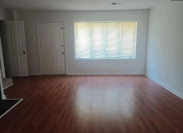 an empty room with wooden floor and windows
