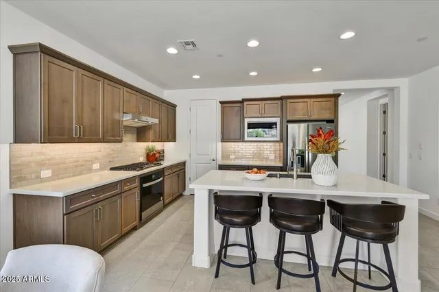 a kitchen with stainless steel appliances granite countertop a stove a sink dishwasher and a refrigerator with wooden cabinets