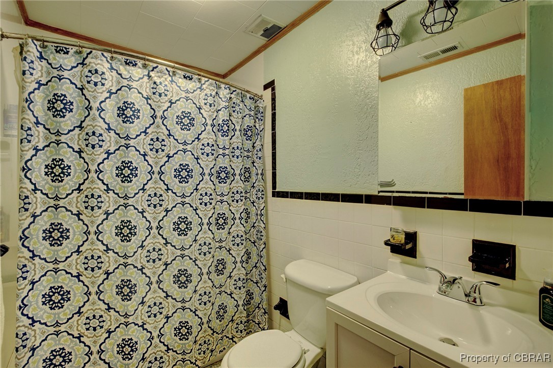 954 Carlton Road Wake, VA 23176 - Photo 9 of 25 Bathroom featuring vanity, a shower with shower curtain, tile walls, and toilet