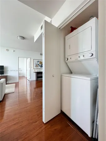a view of empty room with wooden floor and white cabinets