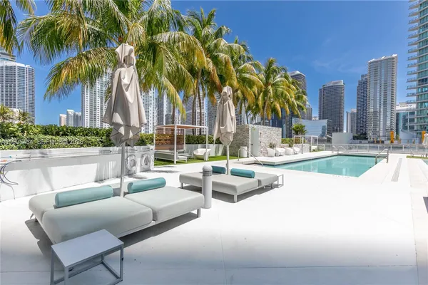 a view of swimming pool with outdoor seating and palm trees