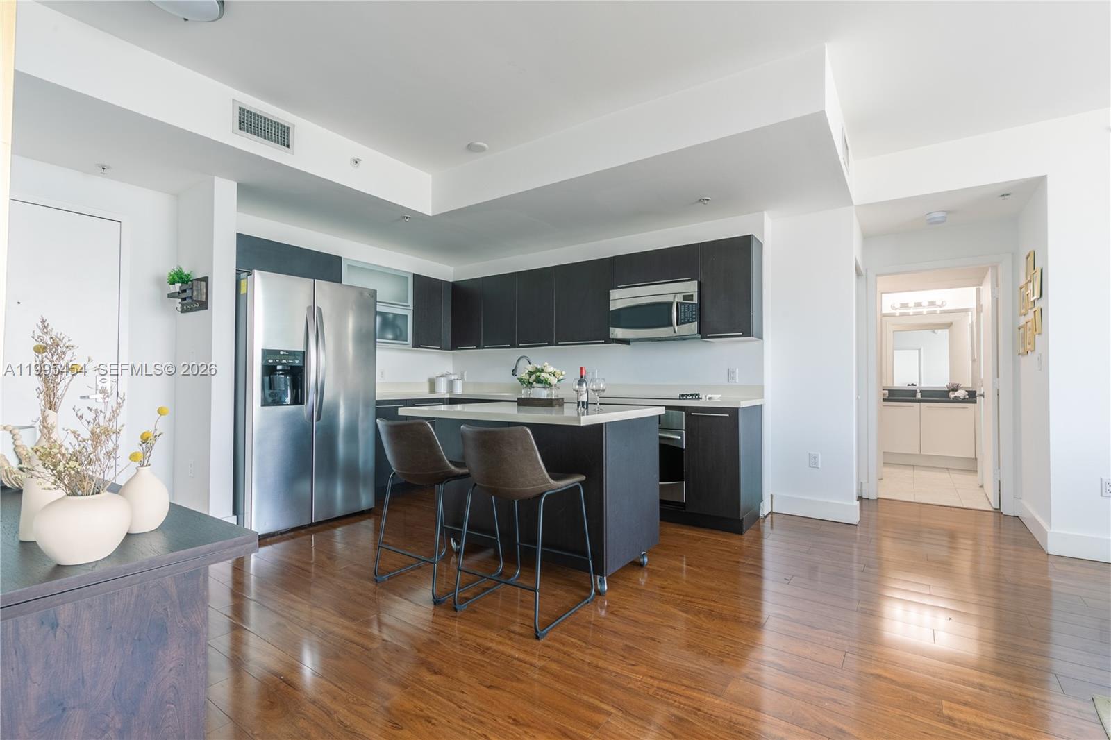 90 Southwest 3rd Street, Unit 3806 Miami, FL 33130 - Photo 4 of 32 a kitchen with stainless steel appliances kitchen island granite countertop a refrigerator a stove a sink a dining table and chairs with wooden floor