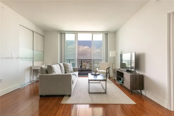 a living room with furniture wooden floor and a large window