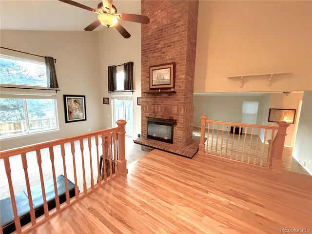 a view of a livingroom with furniture a fireplace wooden floor and windows