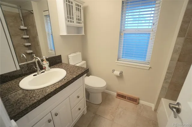 a bathroom with a granite countertop sink toilet a mirror and shower