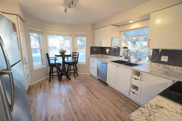 a kitchen with stainless steel appliances granite countertop a dining table chairs stove refrigerator and cabinets