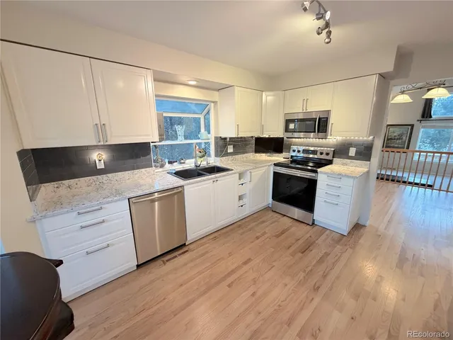 a kitchen with stainless steel appliances granite countertop a stove top oven a sink dishwasher and a refrigerator