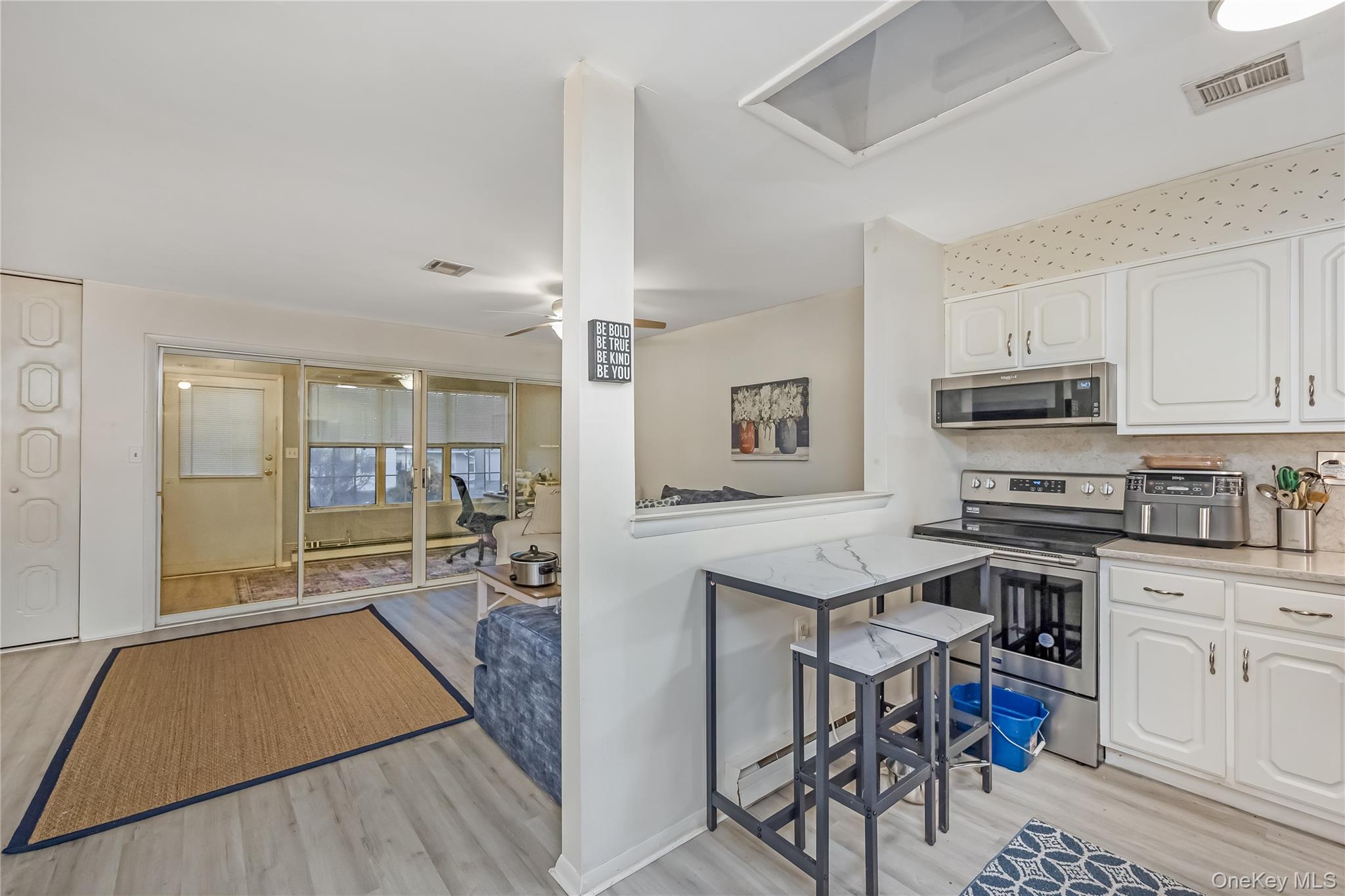 406 Woodbridge Drive, Unit B Ridge, NY 11961 - Photo 11 of 15 a open kitchen with stainless steel appliances granite countertop a stove top oven a sink dishwasher a dining table and chairs with wooden floor