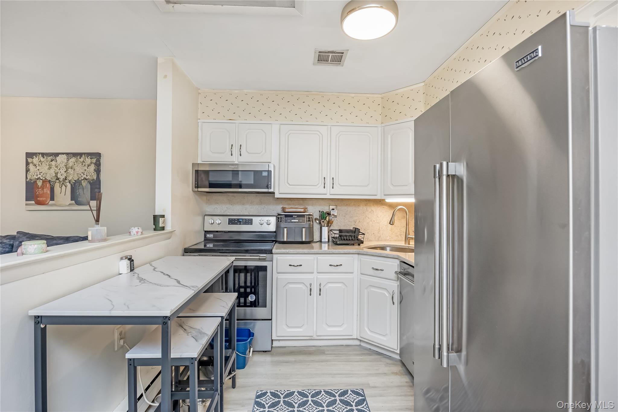 406 Woodbridge Drive, Unit B Ridge, NY 11961 - Photo 9 of 15 a kitchen with stainless steel appliances a stove a sink and a refrigerator