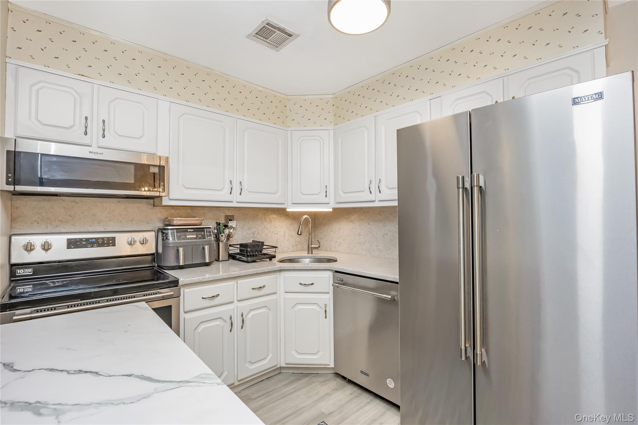 406 Woodbridge Drive, Unit B Ridge, NY 11961 - Photo 10 of 15 a kitchen with stainless steel appliances a refrigerator sink and cabinets