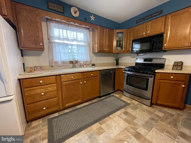 a kitchen with stainless steel appliances granite countertop wooden cabinets a stove top oven a sink and dishwasher