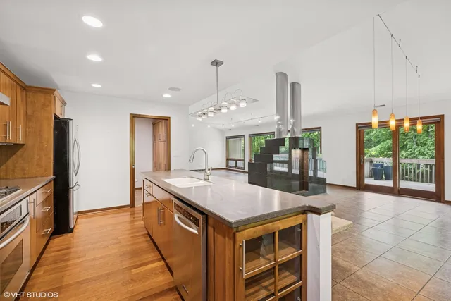 a kitchen with kitchen island granite countertop a table chairs sink and cabinets