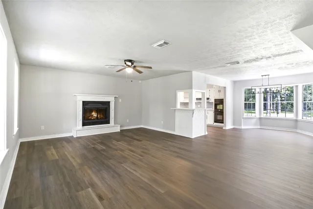 an empty room with wooden floor fireplace and windows
